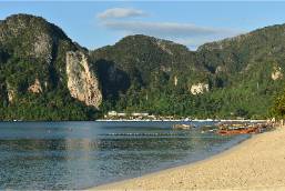 Sandy beach with calm water and forested hills in background