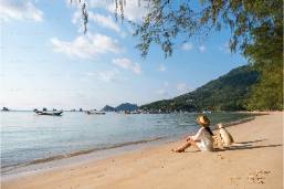 Person sitting on a peaceful sandy beach near the water