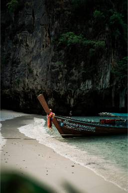 Wooden boat moored on clear water near rocky beach at resort