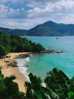 Beachfront area with sandy shore and green hills in distance