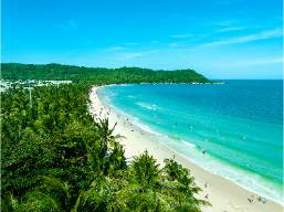 Wide view of a beach with white sand and clear blue water