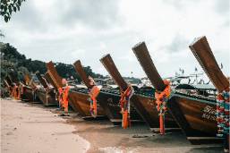 Row of longtail boats lined up on tropical hotel beach shore