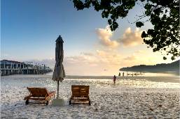 Beach area with lounge chairs and umbrella near calm sea