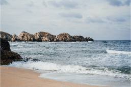 Sandy beach with rocky coastline at oceanfront hotel property