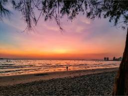 Beach view at sunset near hotel with distant buildings