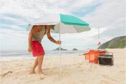 Man setting up sun umbrella on a sandy beach near hotel area