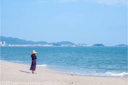 Guest walking alone on hotel beach near the water's edge