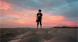 View of a beach area at sunset with a person standing on sand