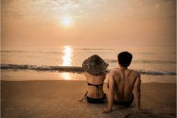 Couple sitting on the beach watching the sunset