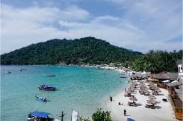 Beach area with sun loungers and boats near hotel waterfront
