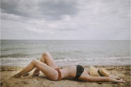 Guest sunbathing on sandy beach by the ocean at the hotel