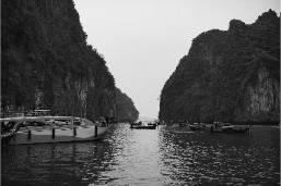 Boats docked in a narrow water passage between cliffs