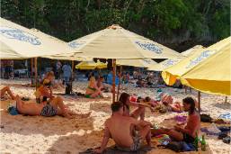 Hotel guests relaxing on a sandy beach under large umbrellas