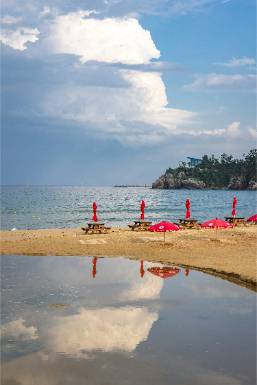 Beach area with lounge chairs and umbrellas near calm water