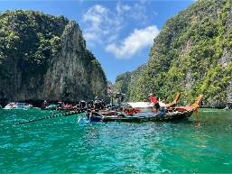 Boats docked near tropical cliffs in a clear water bay