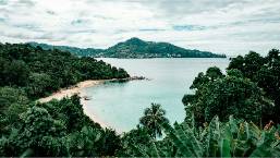 View of a hotel beach area surrounded by lush greenery and hills