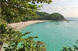 Beach area with turquoise water and tree-lined shore