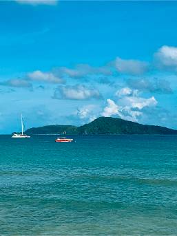 View of beach and ocean with boats and distant island