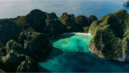 Secluded beach surrounded by rocky cliffs with clear blue water