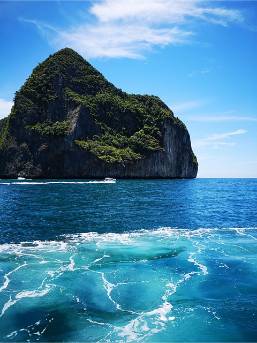 Rock formation surrounded by blue ocean near a hotel beach area